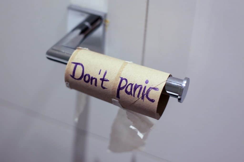 Roll of toilet paper with handwritten message "Don't panic" on it, in a bathroom setting.