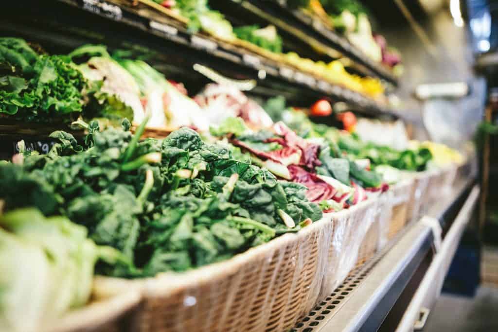 Fresh organic greens and vegetables displayed on a market shelf, highlighting quality and farm-fresh produce.