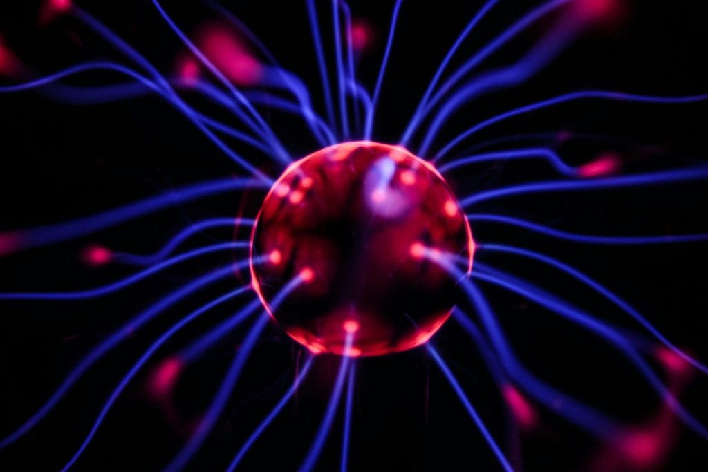 Vivid plasma ball with colourful electric filaments in dark space, showcasing modern science and technology.