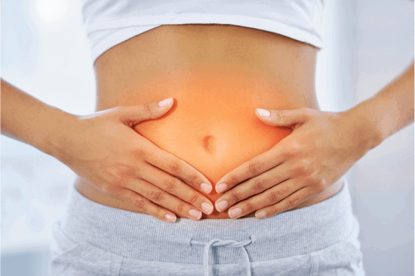 A woman holding her stomach, highlighting digestive health and wellness, with a focus on natural remedies and traditional practices for gut health.